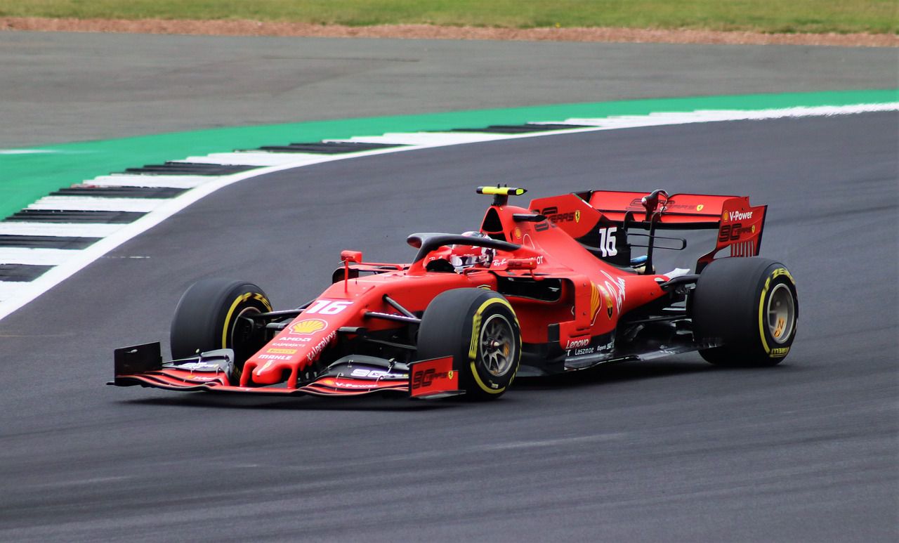 Red F1 car driving towards the left on a race track