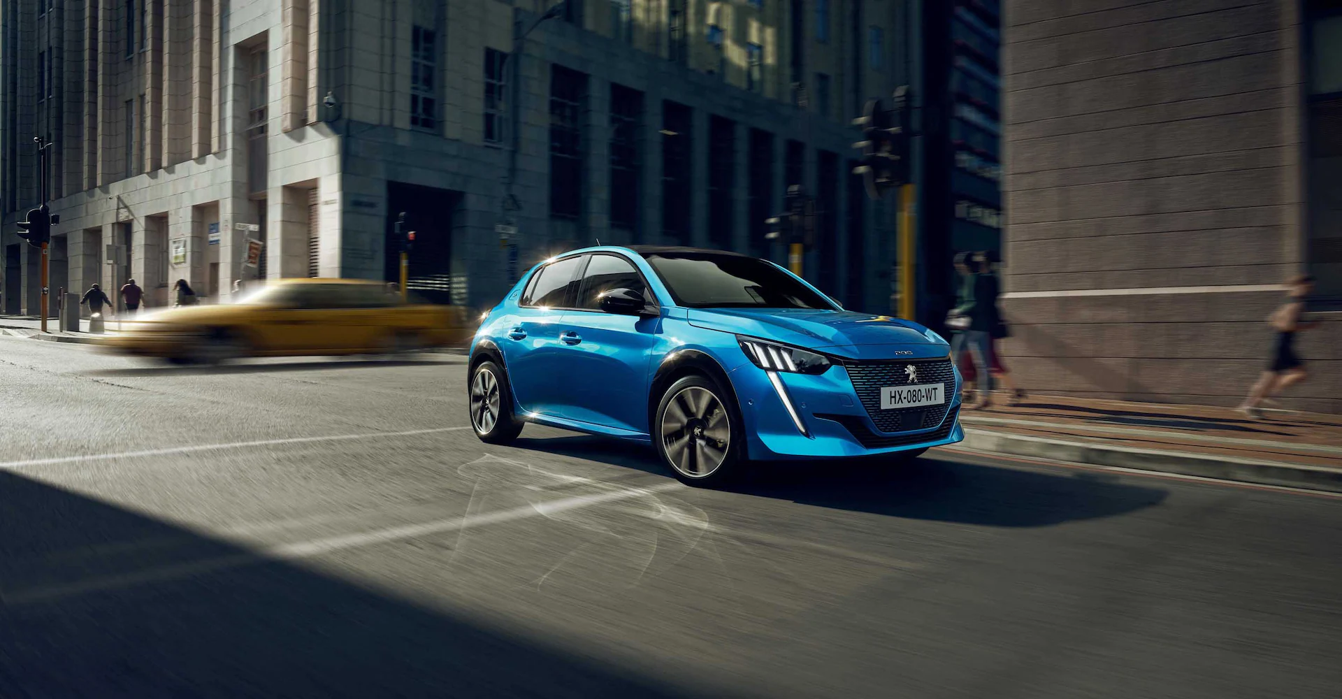 Side view of Blue Peugeot 208 front quarter driving in a city