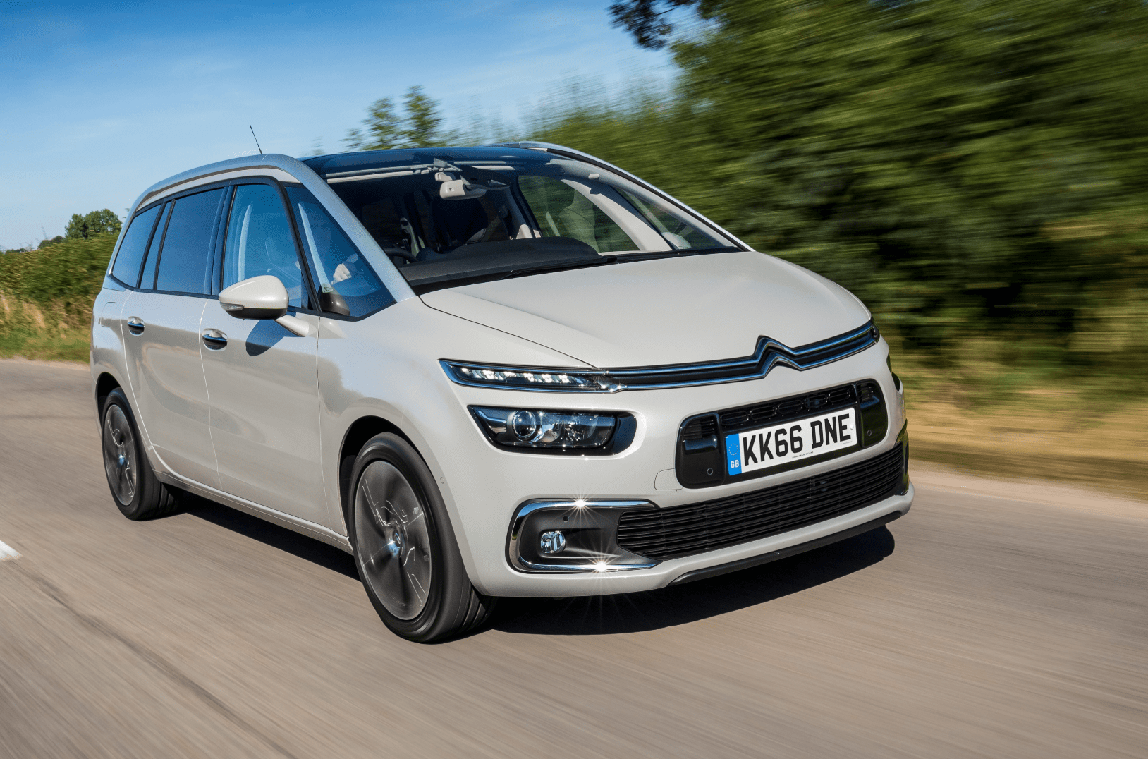 Grey Citroën  C4 Picasso driving on a road surrounded by trees