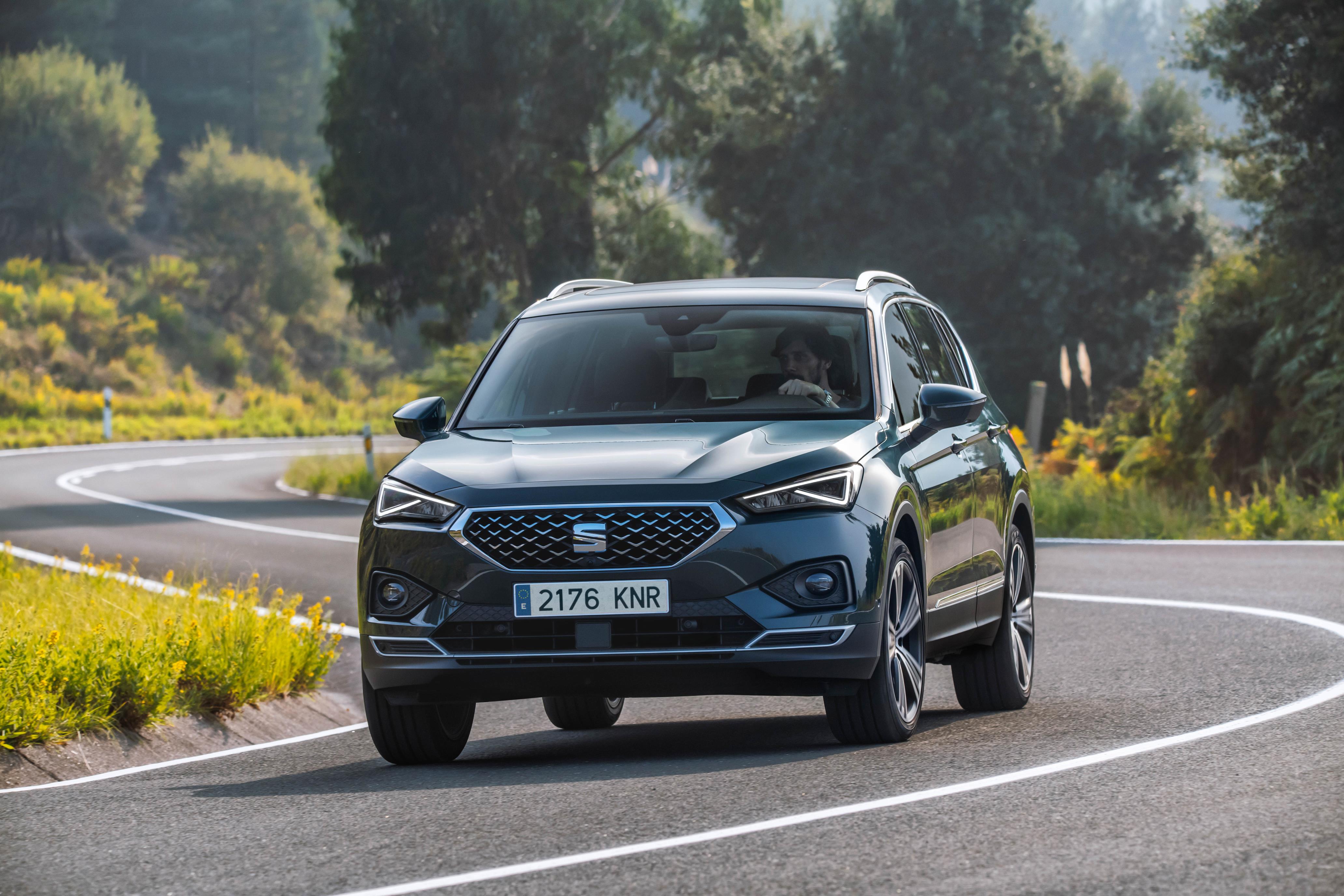 Dark grey SEAT Tarraco driving head on towards you down a winding country lane