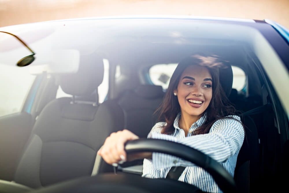 Woman smiling and driving in car