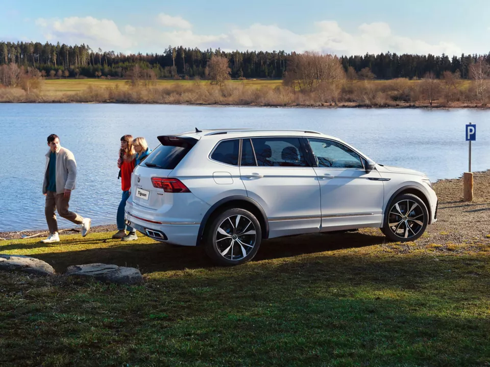 side view of vw tiguan allspace with family walking behind
