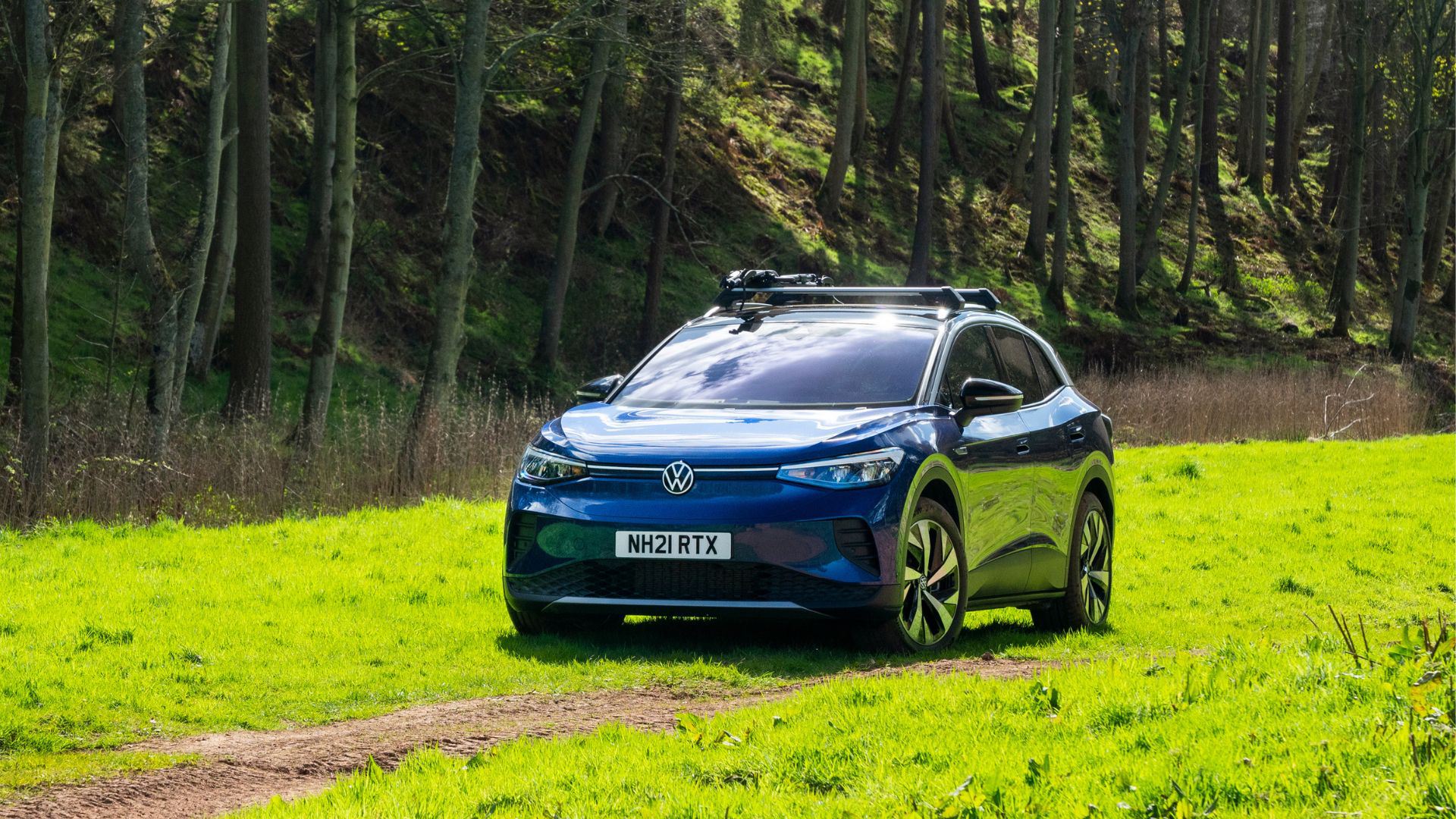Front view of blue Volkswagen ID4 driving across grass